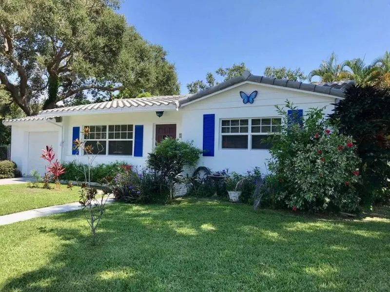 White cottage with blue shutters and a new white tile roof