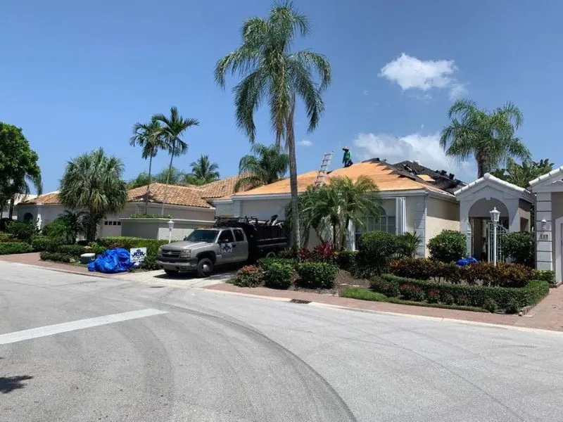 Tile re-roof underway with the old roof stripped and the Mendieta truck at the curb