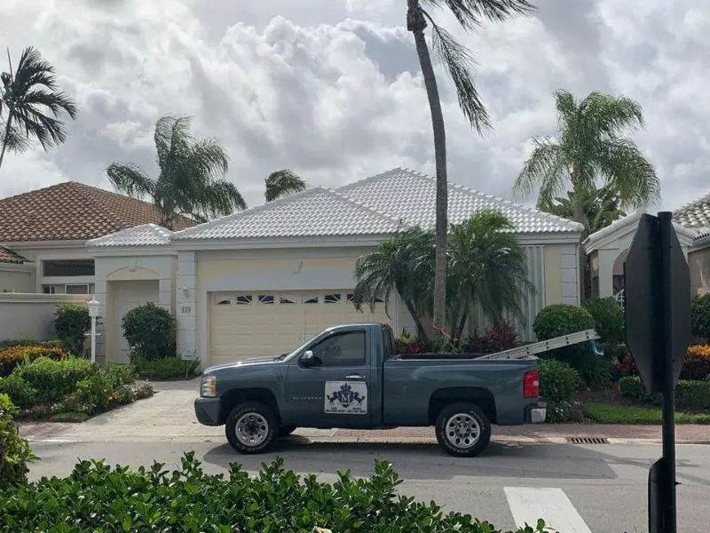 Mendieta Roofing truck with the crest on the door, parked at a white tile roof job
